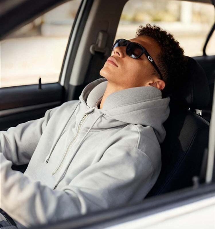 Man wearing light gray inflatable hoodie relaxing in car, road trip lifestyle shot